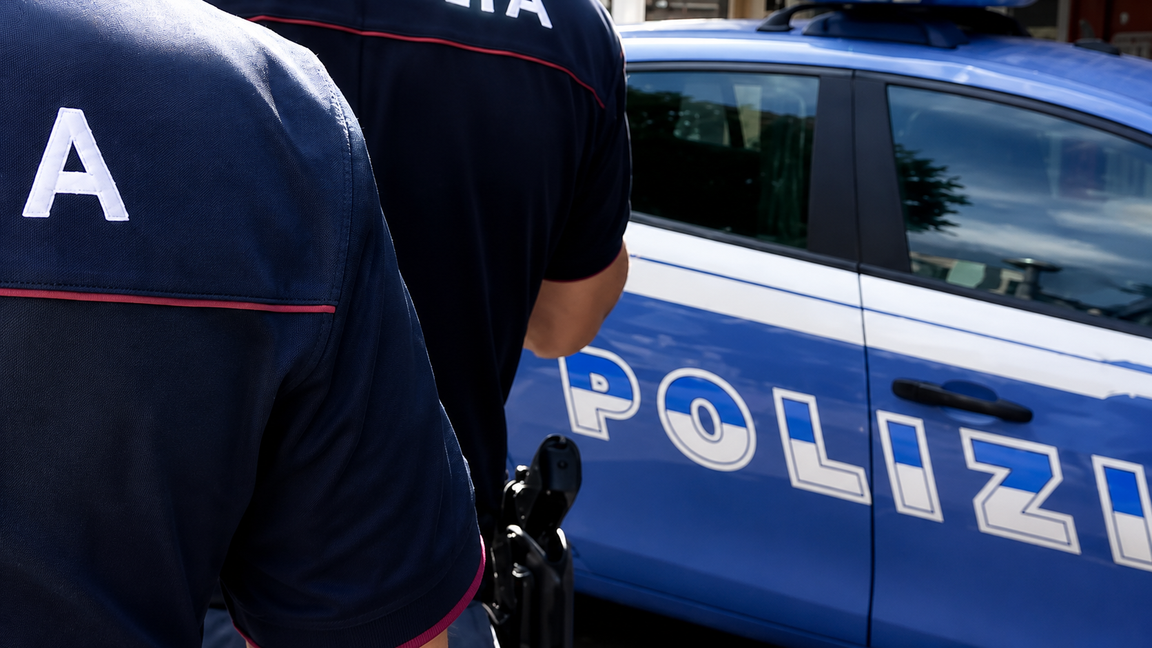 Due agenti della Polizia di Stato vicino a una volante blu durante un servizio di controllo e sicurezza urbana.