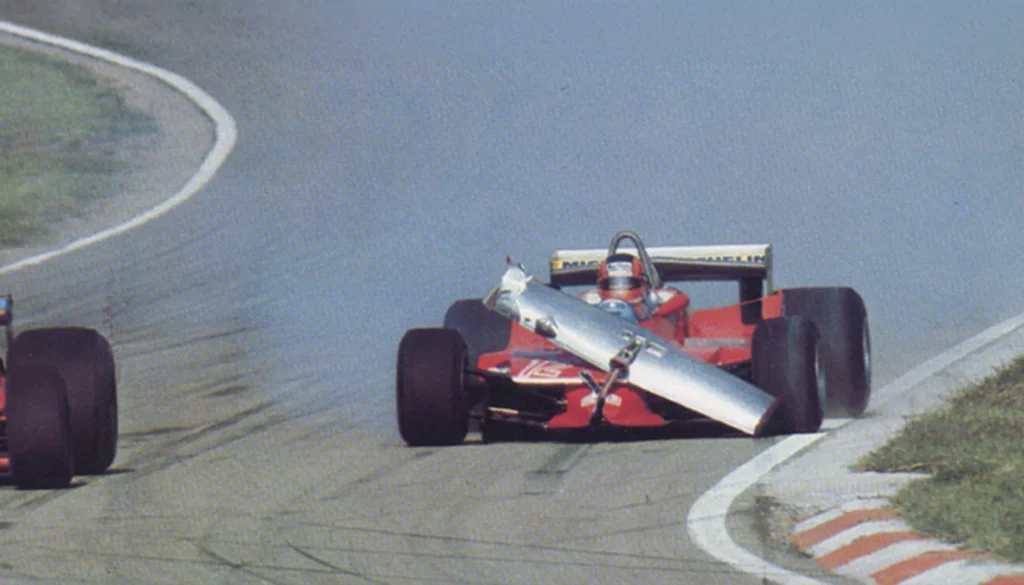 Auto Ferrari di Formula 1 percorre il circuito con una parte dell’alettone anteriore danneggiata e sollevata davanti alla vettura.
