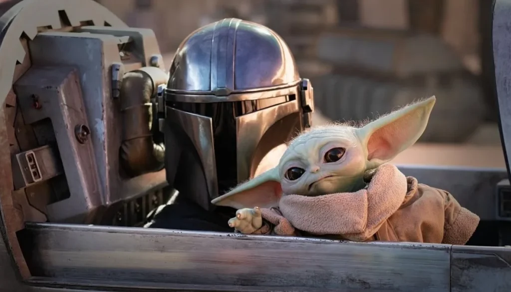 Grogu seduto accanto al Mandaloriano all’interno di una navicella nella serie The Mandalorian.