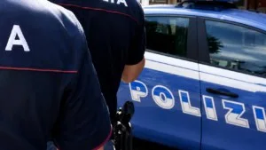 Due agenti della Polizia di Stato vicino a una volante blu durante un servizio di controllo e sicurezza urbana.